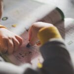 Young child coloring in a workbook, illustrating focus on early childhood education.