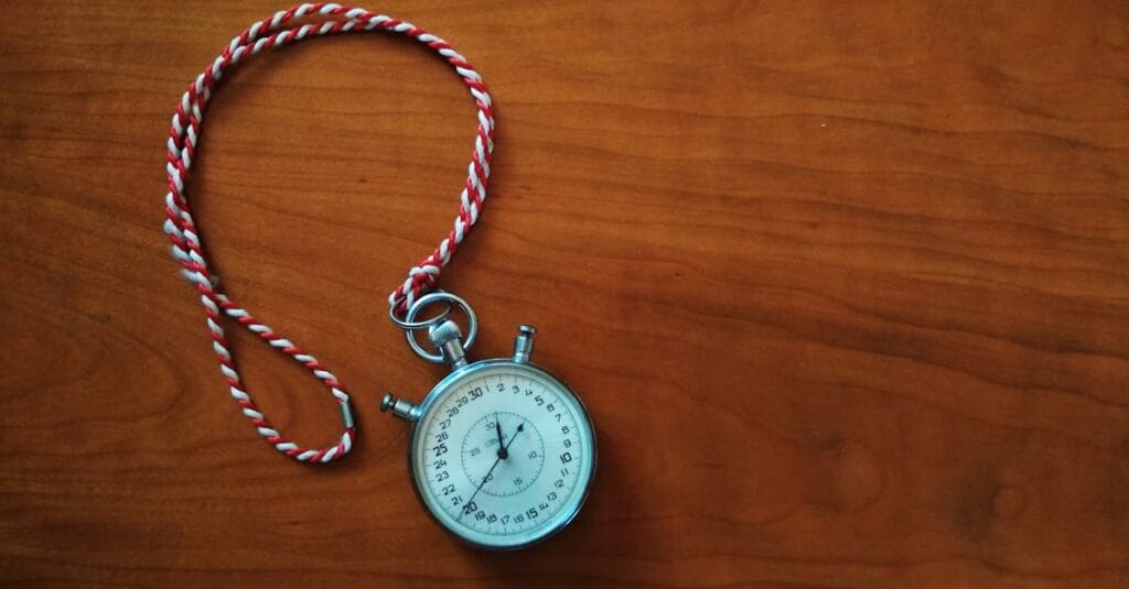 Close-up shot of an antique stopwatch with rope on wooden table.
