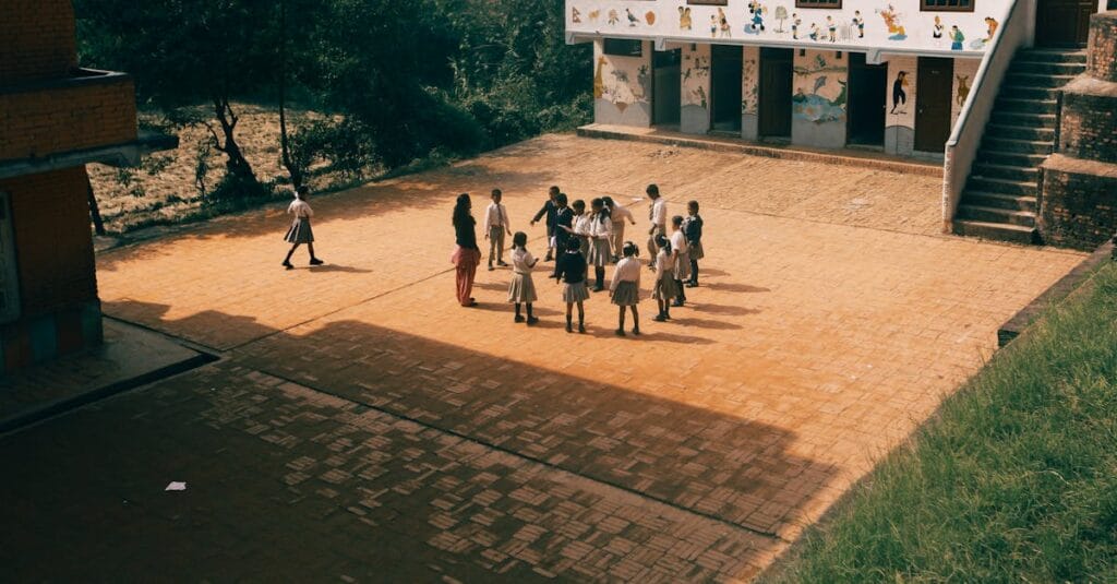 Group of children playing together on a sunny day in a school yard with murals outside.