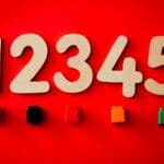 Wooden numbers and colored blocks on a vibrant red background, ideal for educational themes.