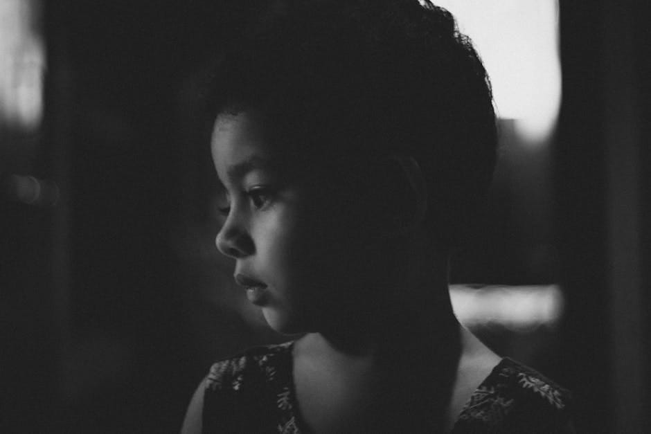 A candid black and white portrait of a thoughtful child in side view.