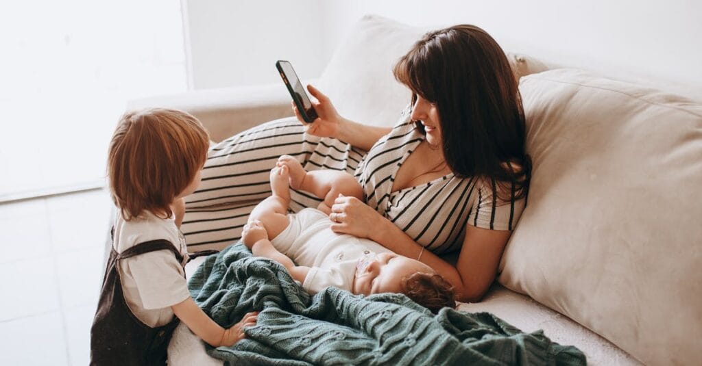 A mother relaxes on a sofa with her two children, enjoying quality time together.