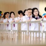A joyful group of students in uniforms holding colorful pinwheels, standing in line.