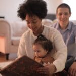 A loving family shares a special moment reading a book together indoors.
