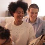 A family shares joyful moments reading a storybook indoors, creating cherished memories.