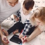 Parents and child enjoying drawing together on the floor, creating memories.