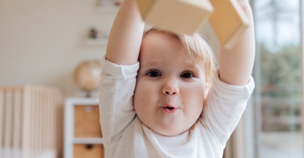 Adorable baby enjoying playtime with wooden blocks in a cozy indoor setting. Perfect depiction of joy and learning.