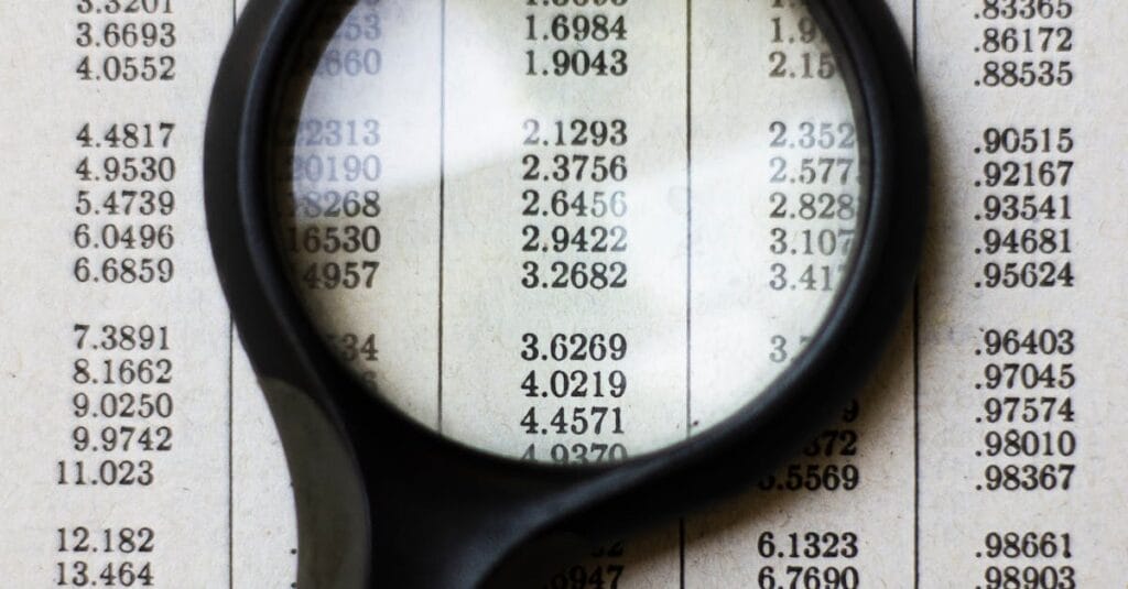 A magnifying glass highlighting mathematical data on a page, emphasizing numbers and calculations.