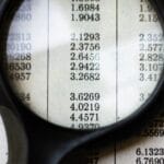 A magnifying glass highlighting mathematical data on a page, emphasizing numbers and calculations.