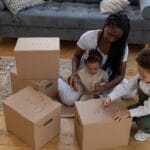 Mother and children packing boxes together in cozy living room environment.