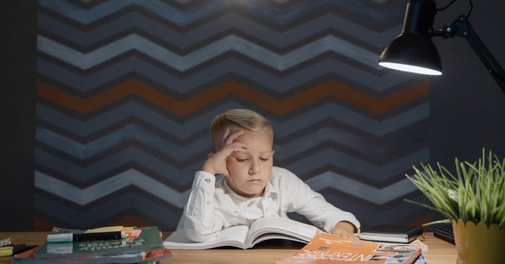A young boy engaged in study at a desk, illuminated by a lamp, with books and a plant nearby.