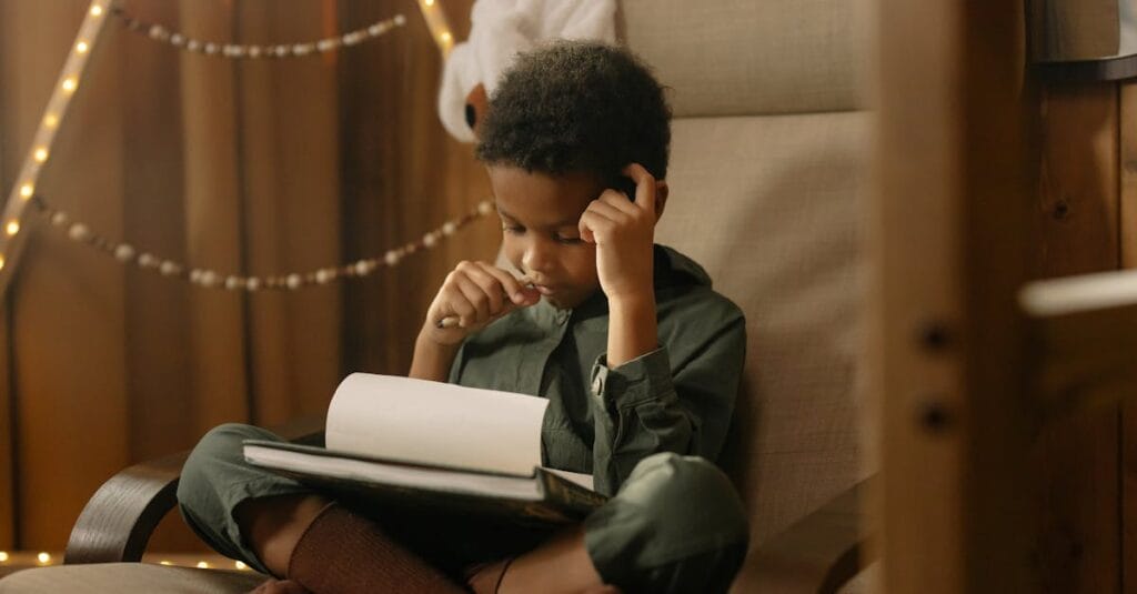A young child intensely focused on drawing while sitting indoors in a cozy and warm setting.
