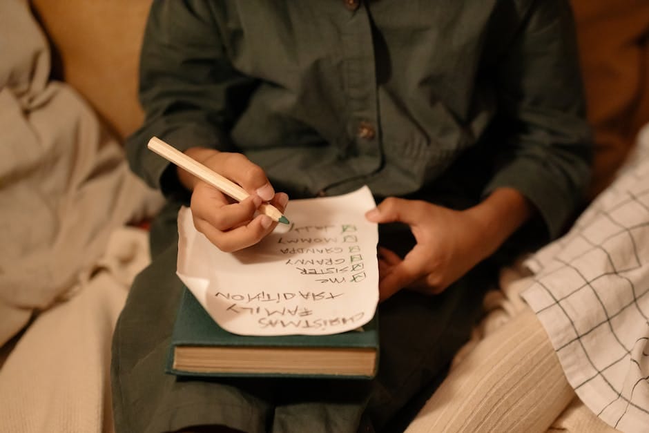 A child writes a Christmas wish list with green pencil on cozy winter evening. Family tradition and holiday joy.