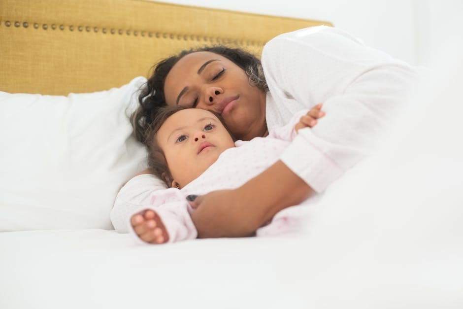 A mother and her baby with Down syndrome sleeping together in bed.