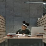 A person immersed in study at a library surrounded by card catalog drawers.