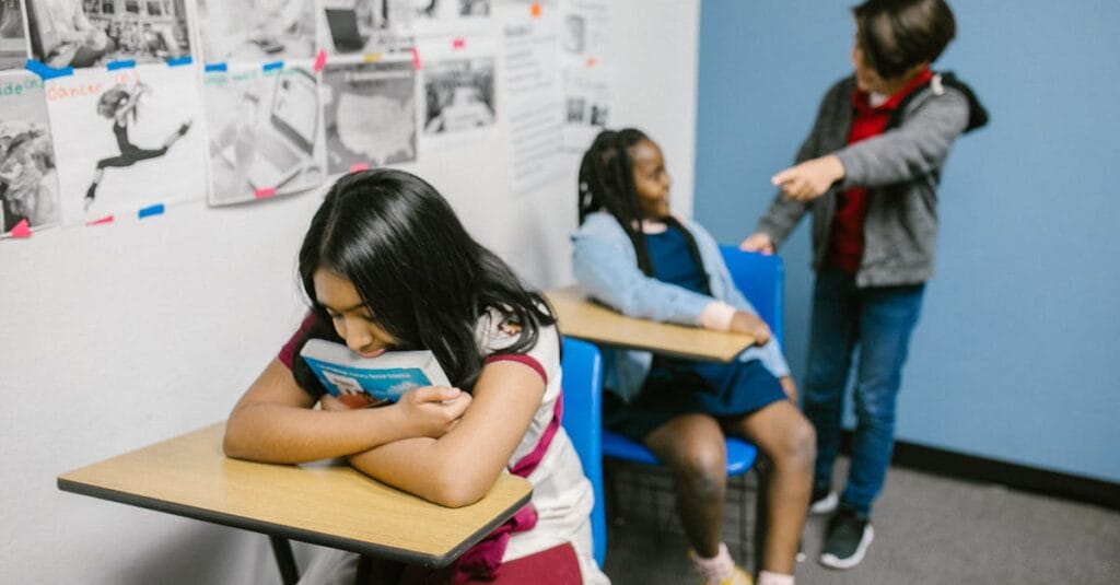 A sad girl in a classroom being bullied by classmates, highlighting anti-bullying awareness.
