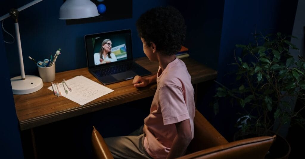 A child participating in an online learning session at a home desk with a laptop.