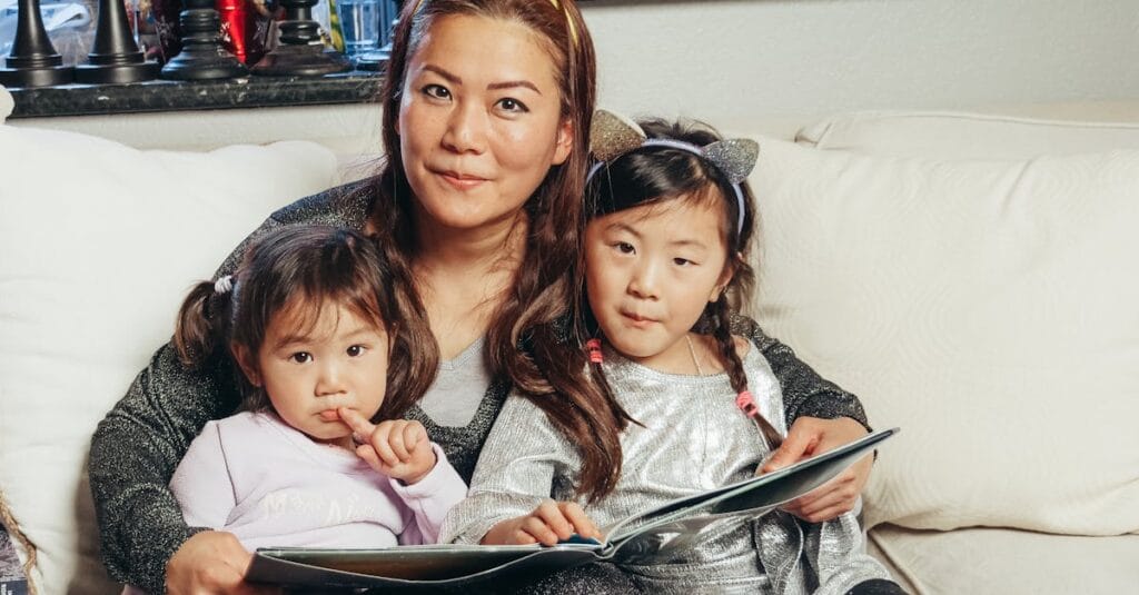 Cozy family moment with a mother reading a book with her daughters on a couch.