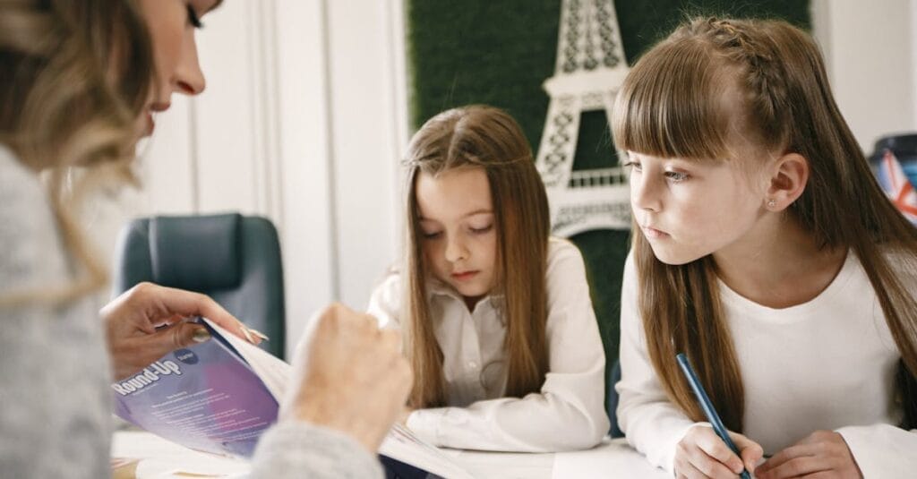 Two girls attentively studying with a tutor in a classroom setting.