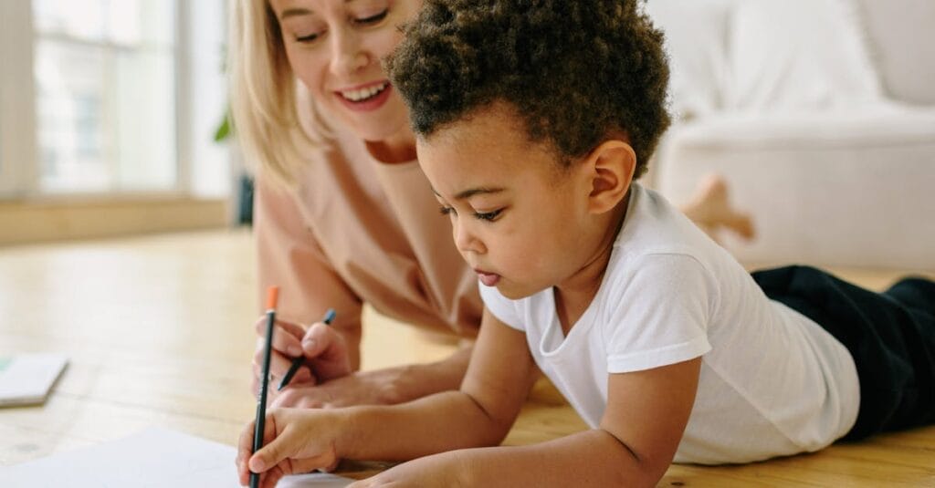 Mother and son bonding through drawing at home, fostering creativity and connection.