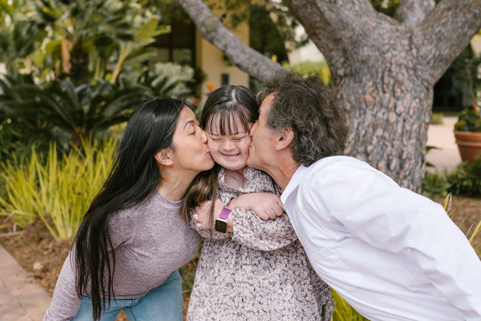 Happy parents kissing their daughter with Down syndrome in a loving outdoor setting.