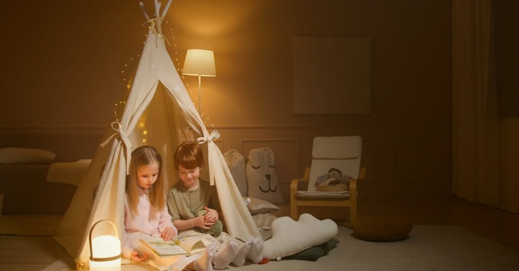 Two children enjoy a bedtime story inside a cozy indoor tent, creating a warm and inviting atmosphere.