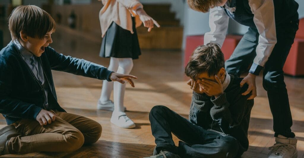 Group of kids bullying another child at school, signaling peer pressure and harassment.
