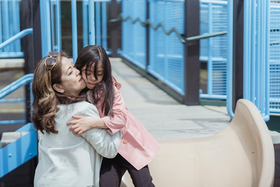 A heartwarming moment between a mother and daughter enjoying time together at a sunny playground.