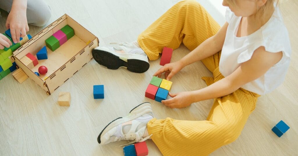 A young child playing creatively with colorful wooden blocks indoors, fostering learning and development.