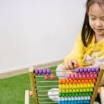 A young girl enjoying an educational moment with a vibrant abacus, teaching counting and fun.