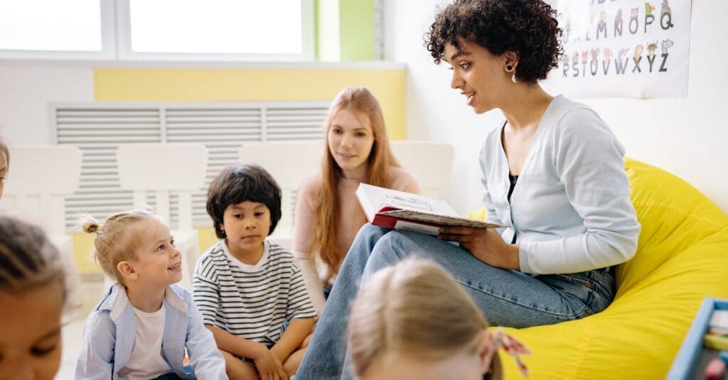 Teacher reading to preschool kids in a colorful classroom setting.