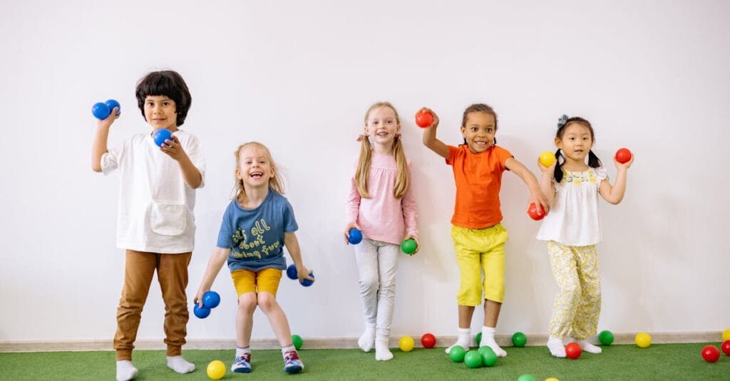 Happy diverse children playing with colorful balls indoors, showcasing fun and friendship.