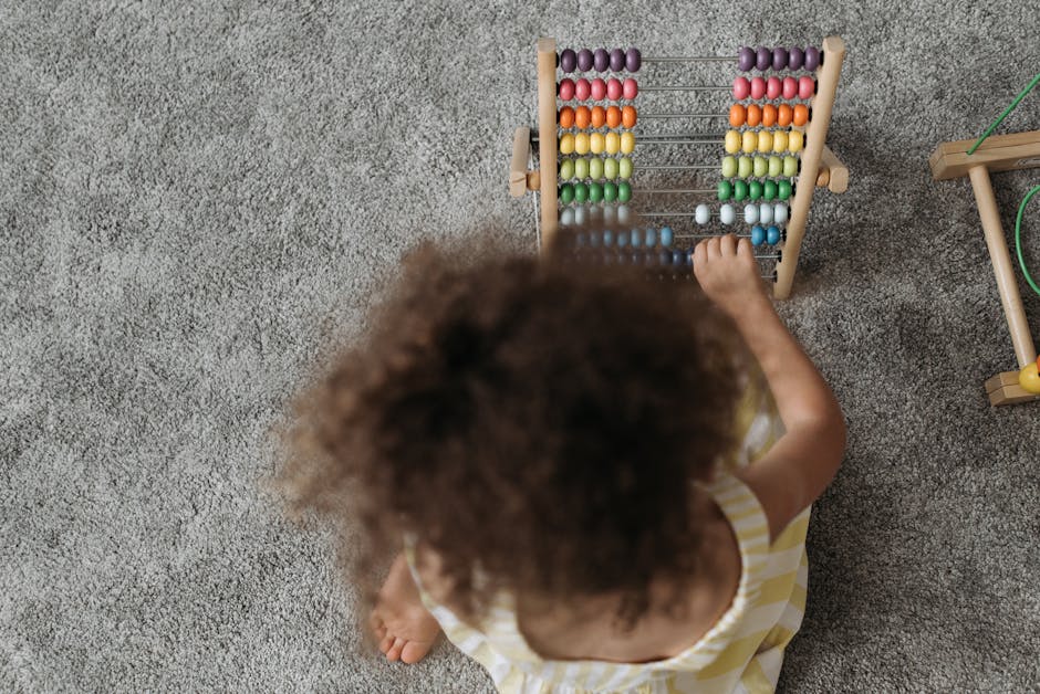 A young girl engaging with a colorful wooden abacus on a carpet, showcasing playful learning.