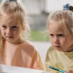 Twin girls focused on an online learning activity using a laptop.