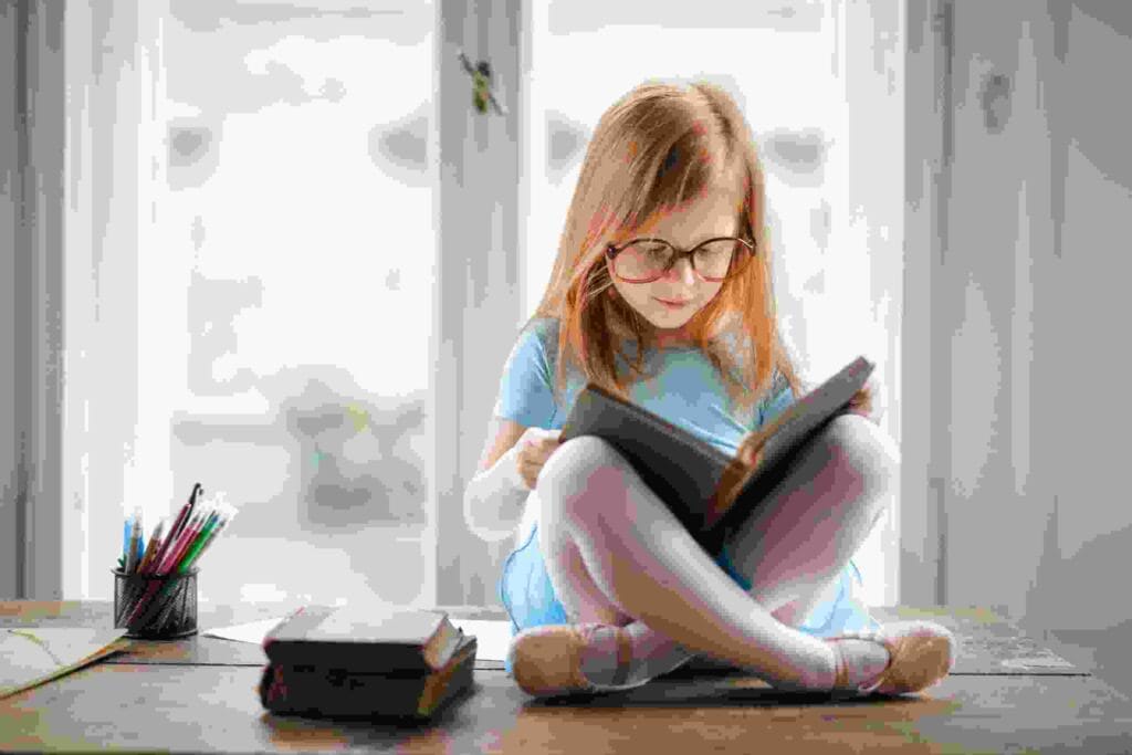Terapi Calistung - Anak kecil sedang duduk didepan jendela sambil membaca buku