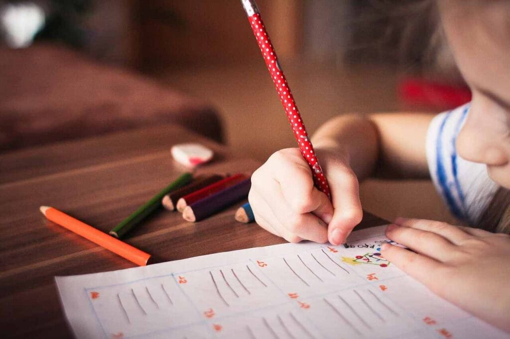 Terapi Calistung - Anak yang sedang menulis dengan pensil merah