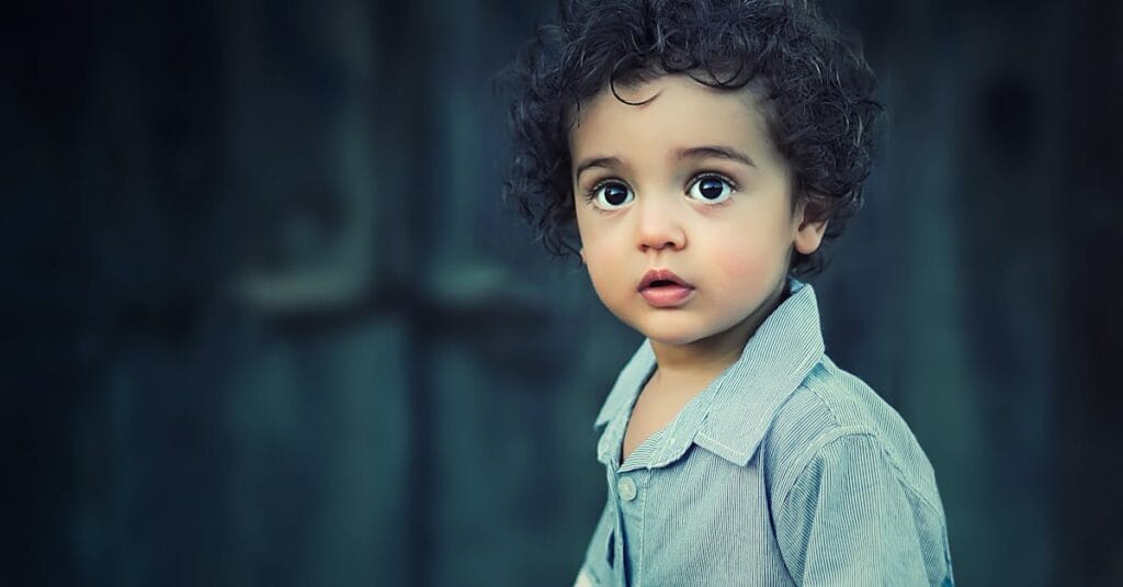Charming portrait of a young boy with curly hair and striking eyes.