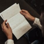 Close-up of a man holding and reading a handwritten letter with personal content.