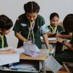 A group of girls in school uniforms studying together in a classroom setting.