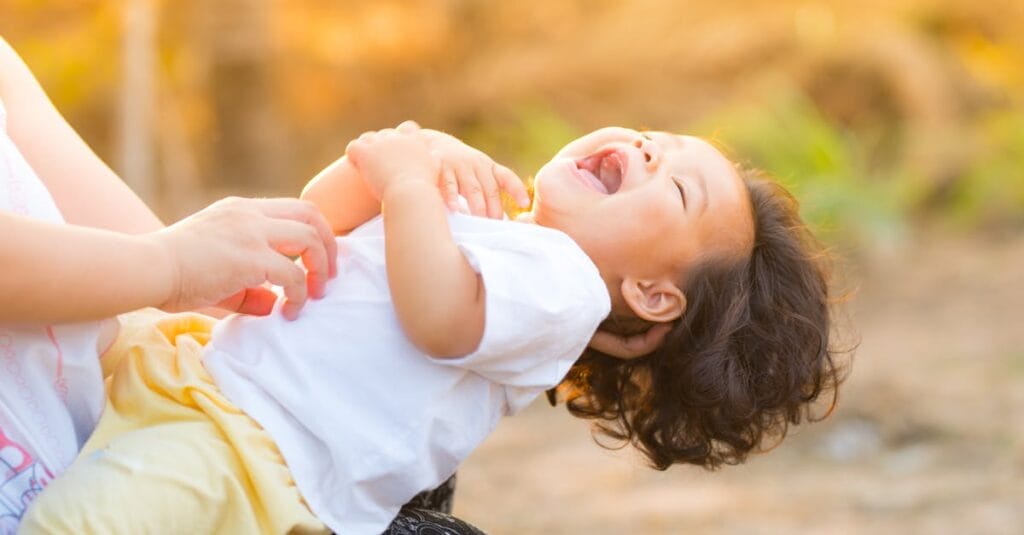 A happy baby enjoying playful moments outdoors, captured in warm summer lighting.