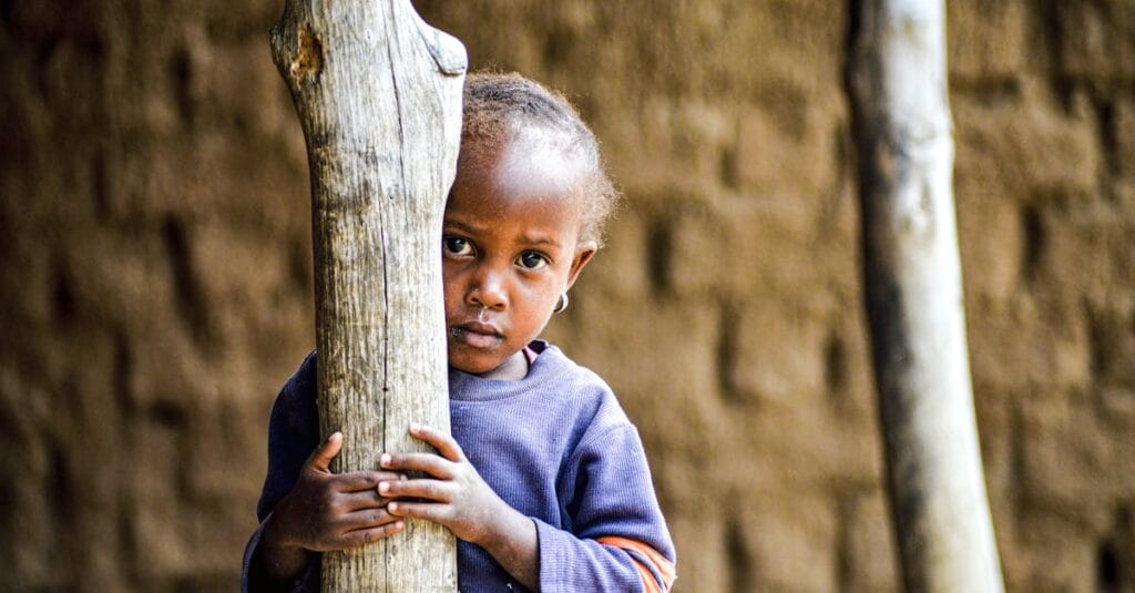 Portrait of a shy child peering behind a tree in Dodoma, Tanzania.