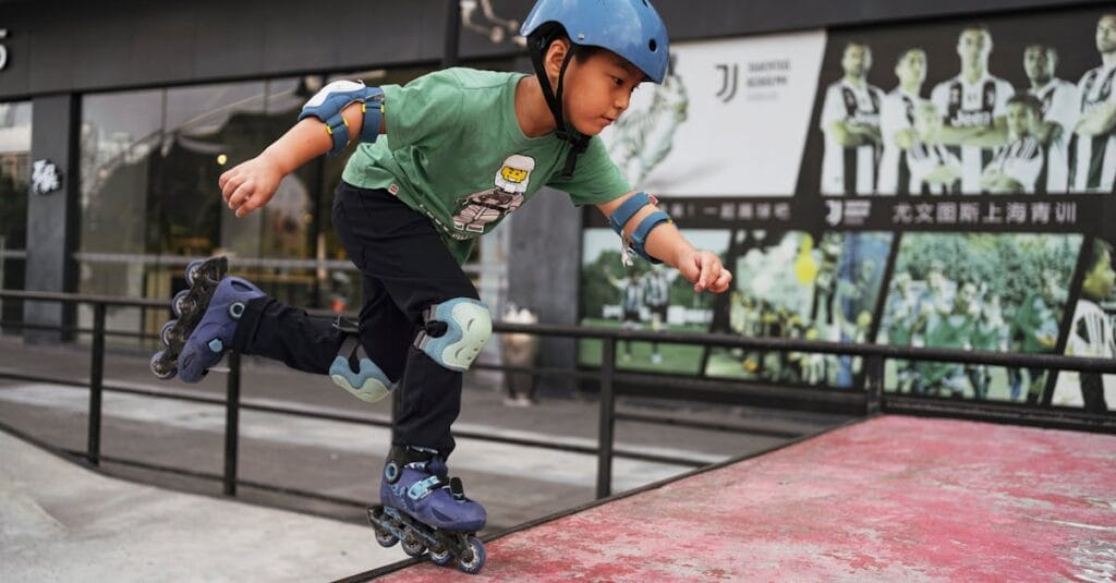 A boy performing a move on roller skates at a skatepark, wearing protective gear.
