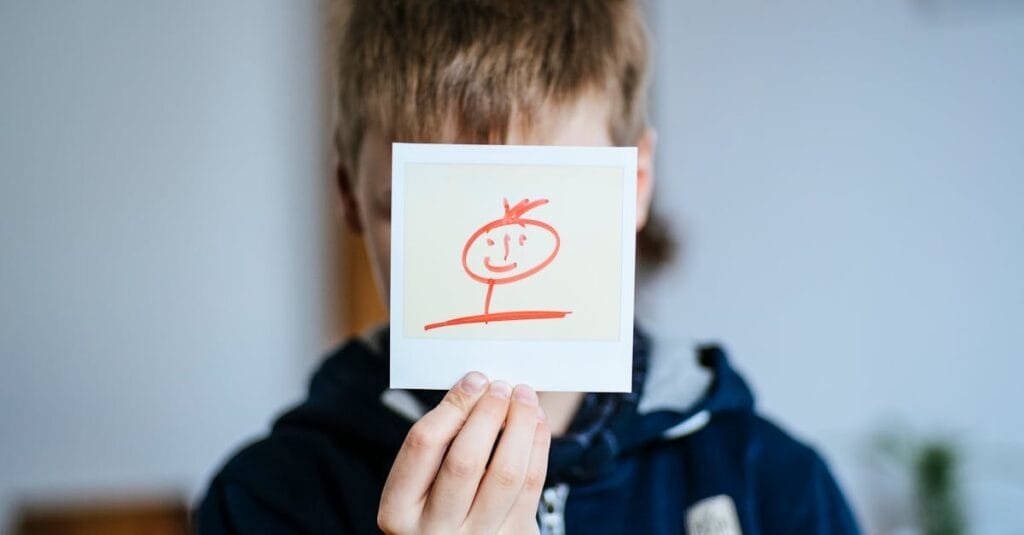 A child holding a hand-drawn stick figure portrait indoors.