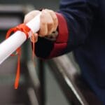 A close-up image of a graduate holding a diploma tied with a red ribbon, symbolizing achievement and success.