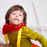 Young child posing indoors with a playful expression and bright clothing.