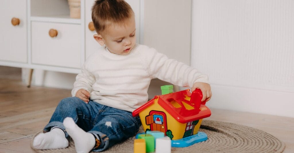 Young boy engages with colorful educational toy inside a cozy home environment.