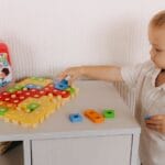 Young boy engaged in play with a colorful educational toy set indoors.