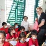 A teacher handing out gifts to students in a Vietnamese classroom.