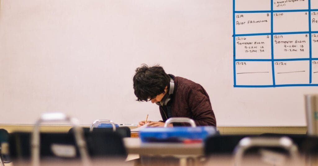A high school student studying and solving problems in a classroom setting.