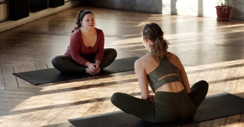 Two women practicing yoga indoors, embracing diversity and wellness.